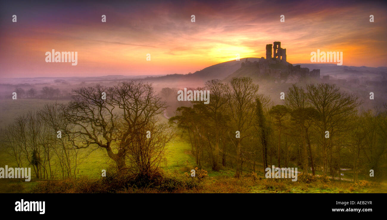 Derelict castle at Corfe Castle near Swanage Dorset with the orange glow of pre dawn in the sky and swirling mist in the valley Stock Photo