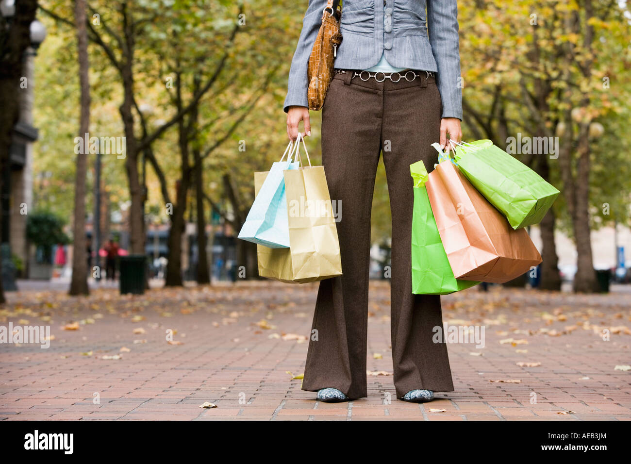 Woman holding shopping bags in urban park Stock Photo - Alamy