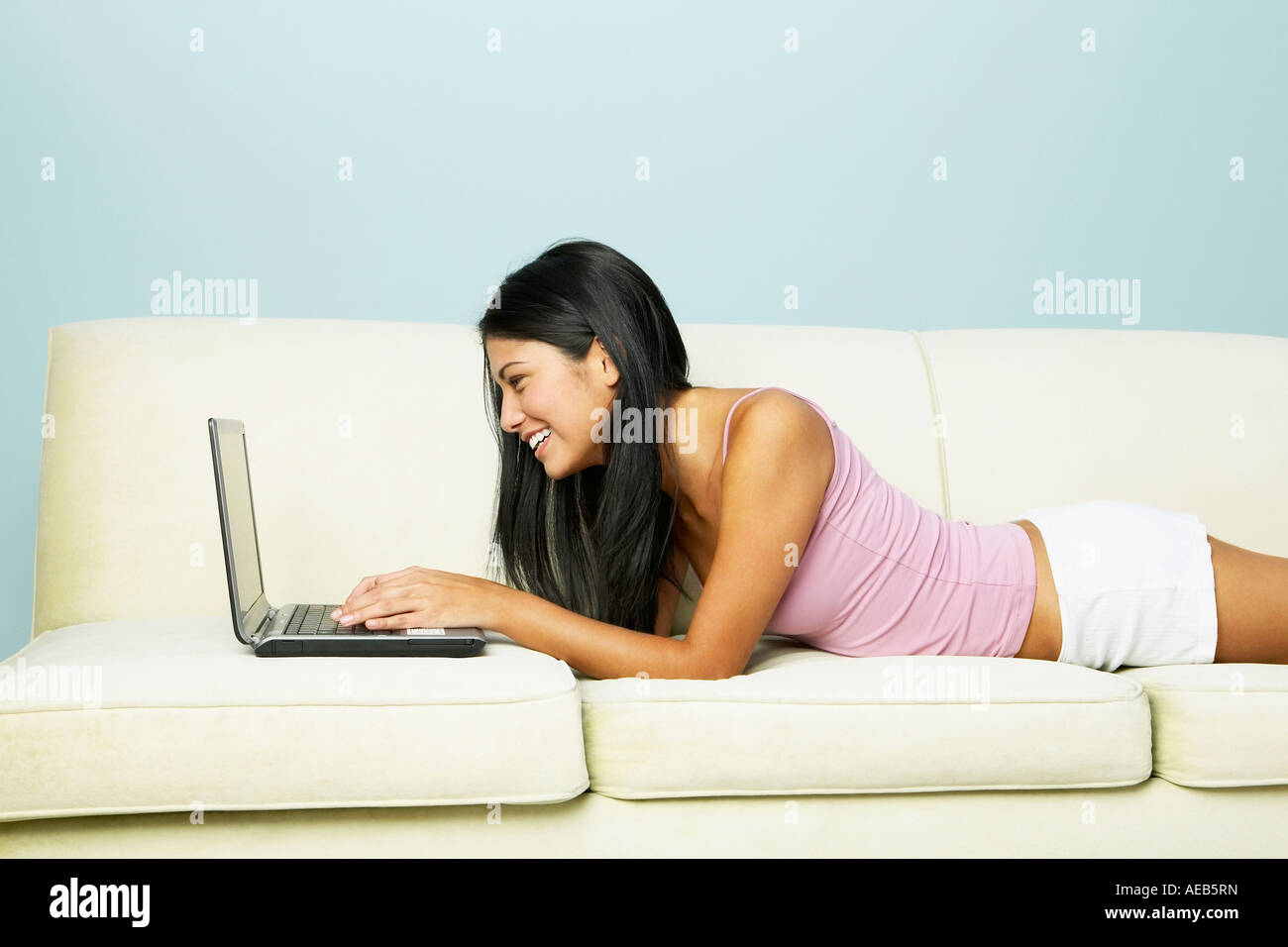 Young Hispanic woman using laptop on sofa Stock Photo