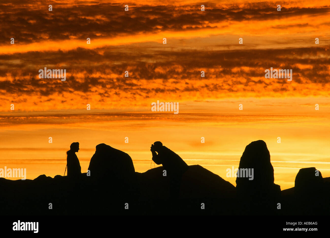 A couple taking a photograph at sunset at Castlerigg Stone circle, Keswick, Lake District, UK Stock Photo