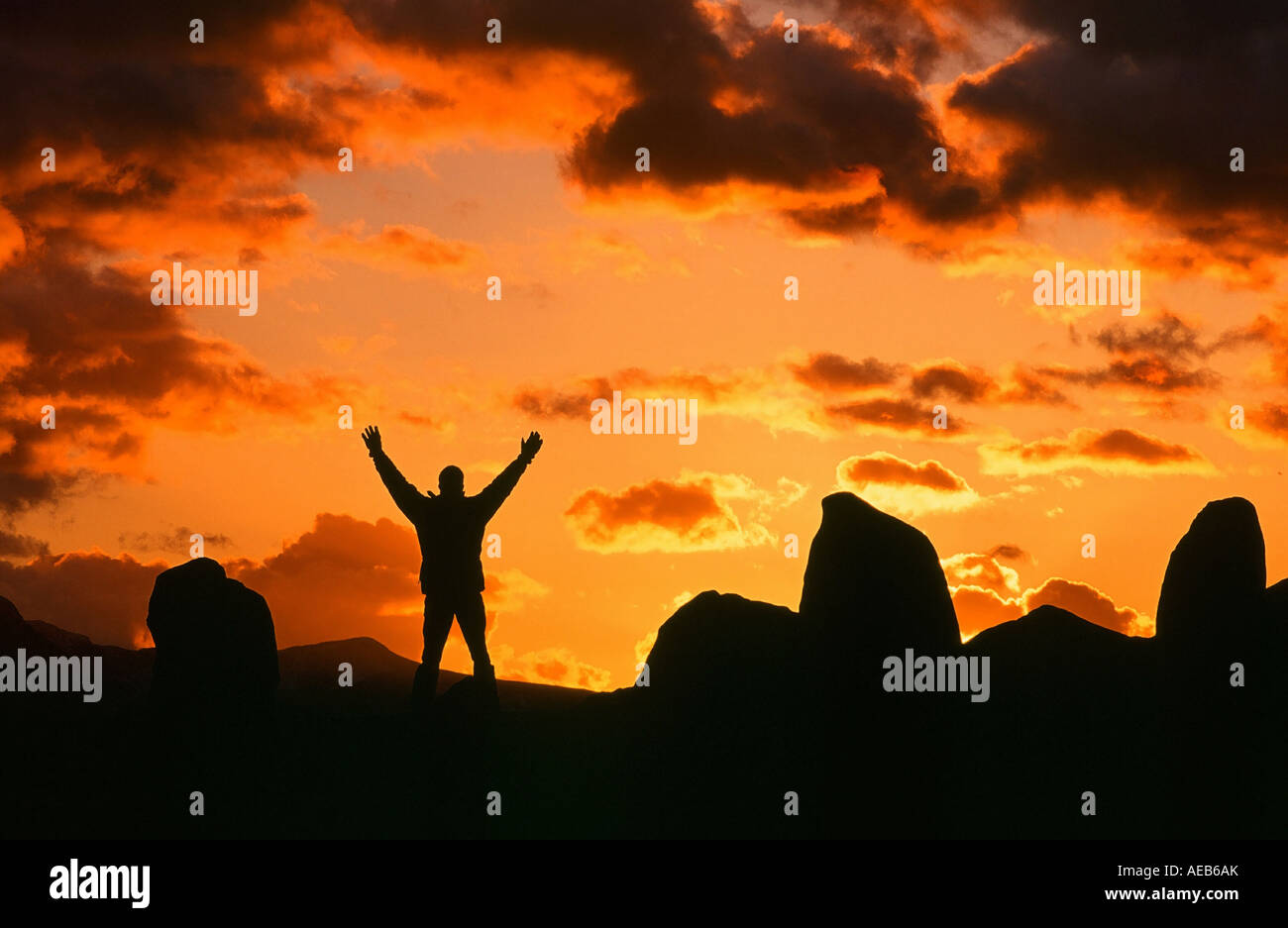 A man celebrating the winter solstice at sunset at Castlerigg Stone circle, Keswick, Lake District, UK Stock Photo