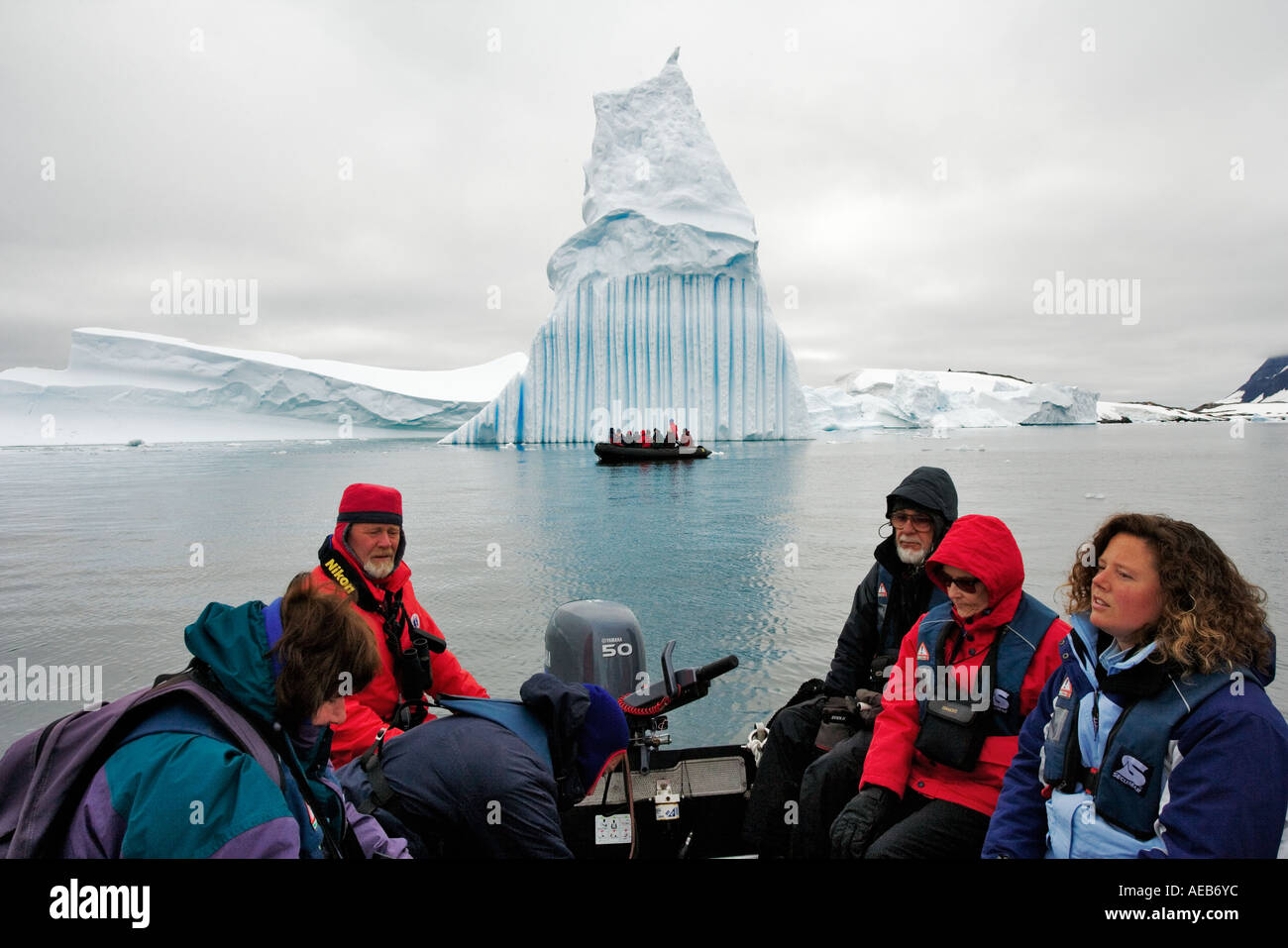 Iceberg viewed by tourists Tourists in a zodiac viewing a ragged edged iceberg Antarctica Stock Photo