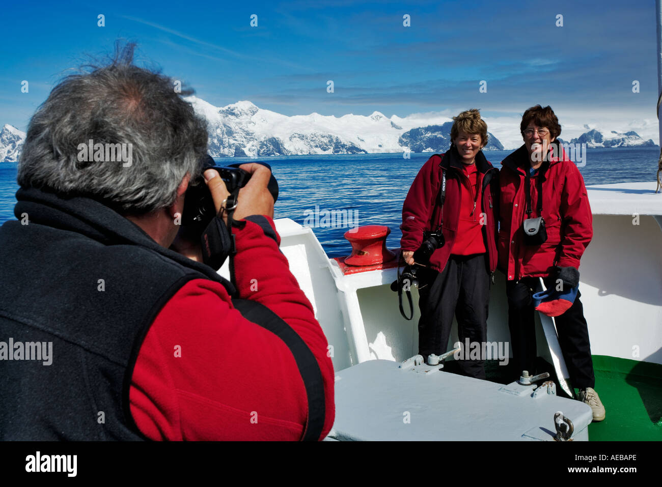 Tourists taking pictures of each other with iceberg in background Antarctica Stock Photo
