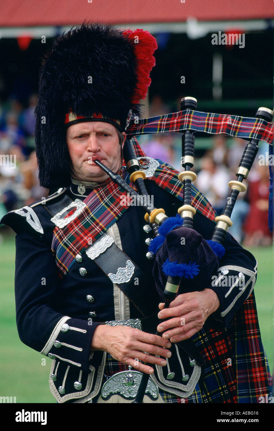 Scotsman plays Bagpipes at Braemar Games Royal Highland gathering in tartan costume and busby style hat Scotland Stock Photo