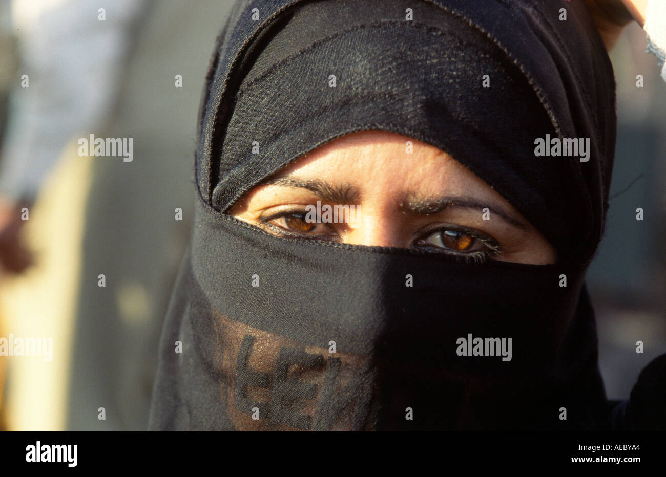 A Moroccan woman wearing a black headscarf looks directly at the camera
