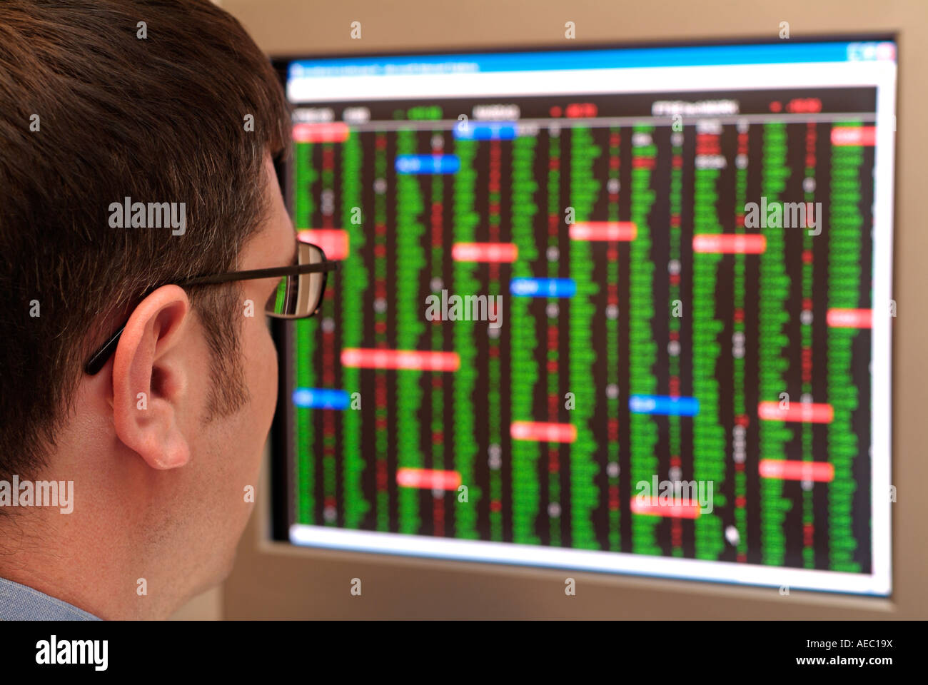 Stockbroker Looking at a Monitor Screen Full of Share Prices Stock Photo