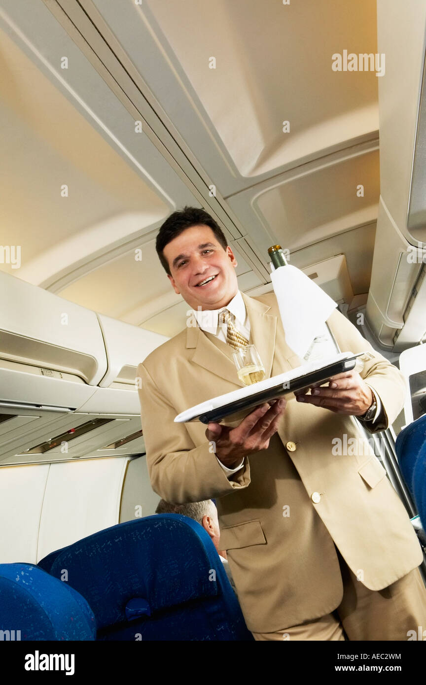 Low angle view of Hispanic male flight attendant carrying wine on a tray  Stock Photo - Alamy