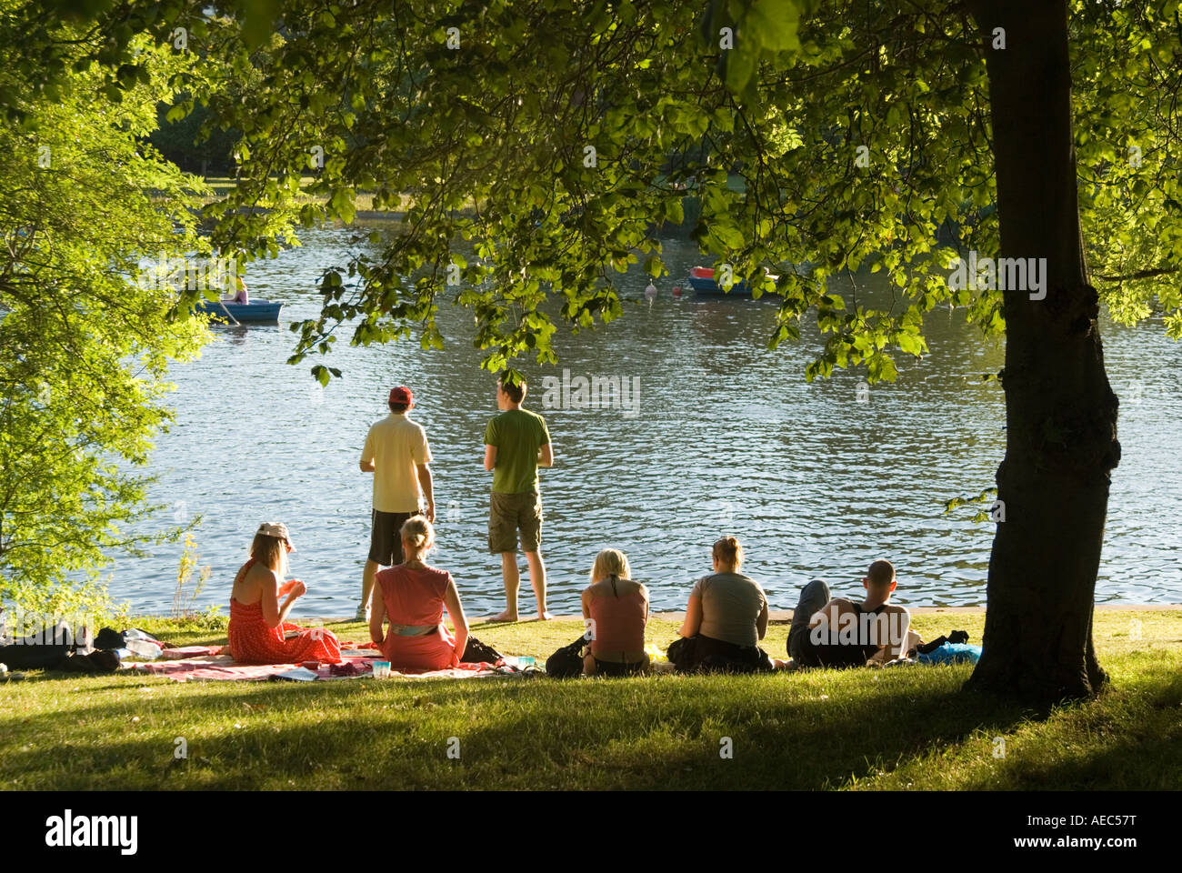 Young people relaxing on summer day beside the lake in Regent's Park London England UK Stock Photo