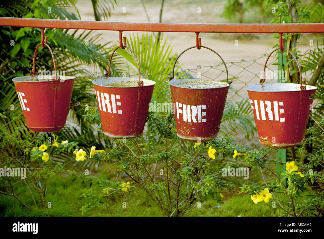 Four red buckets filled with sand and painted Fire hanged serially near a petrol bunk in Kerala India Stock Photo