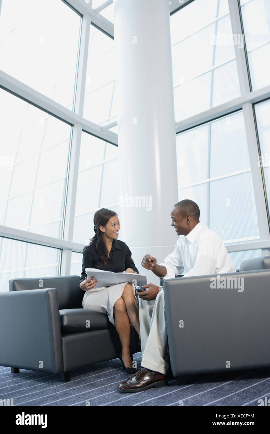Businessman and businesswoman talking in office lobby Stock Photo - Alamy