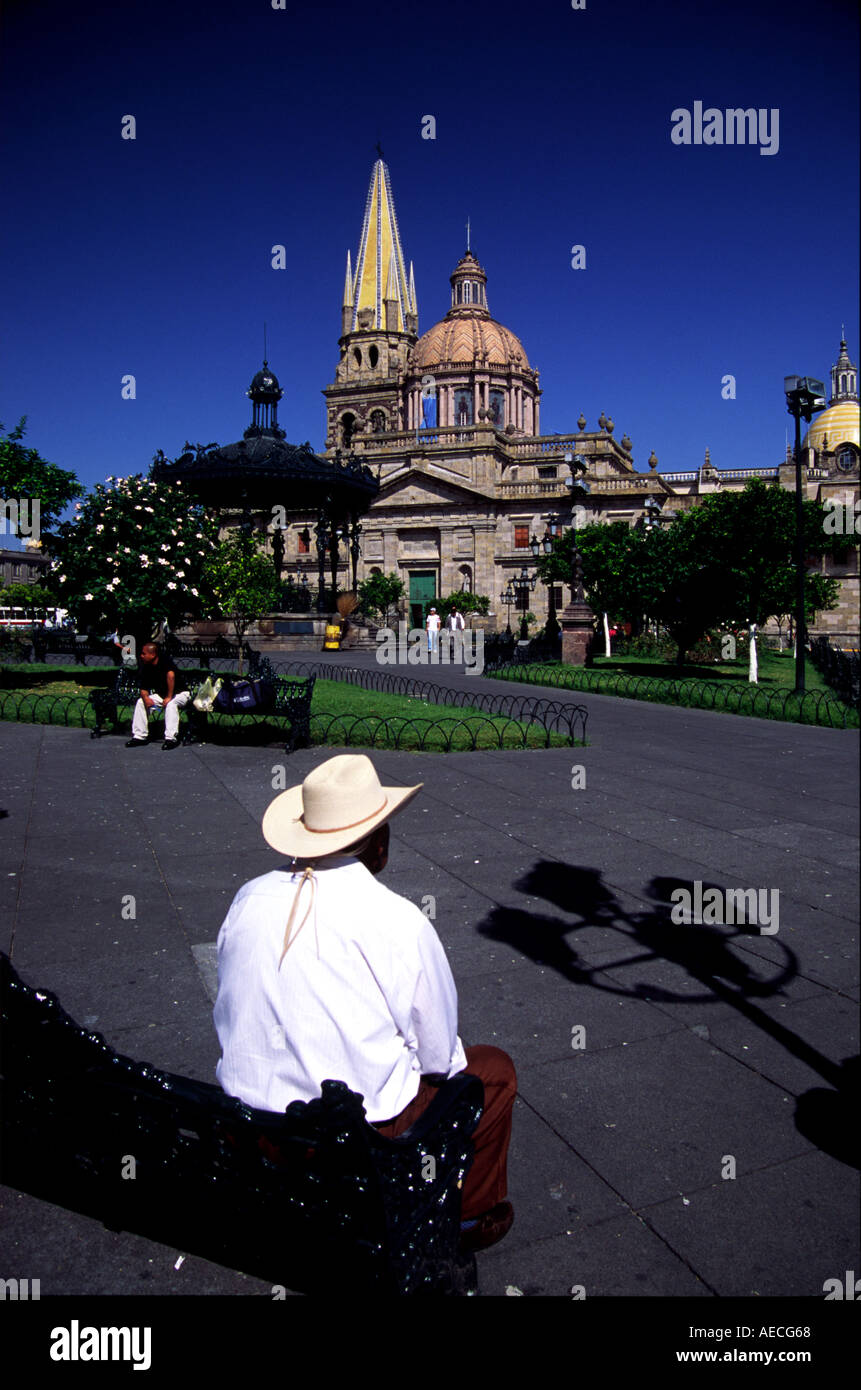 A street scene in the central plaza of Guadalajara Mexico A man sits on a bench in front of the central cathedral Stock Photo