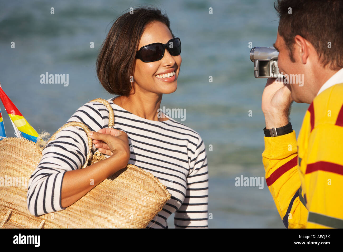 Indian man video recording girlfriend at beach Stock Photo