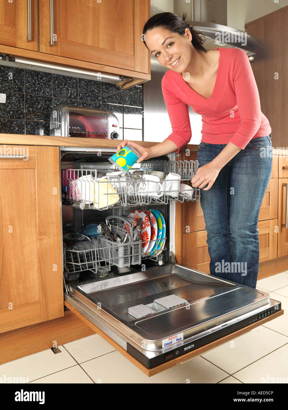 Young Woman Filling Or Emptying A Domestic Dishwasher With Dishes In A