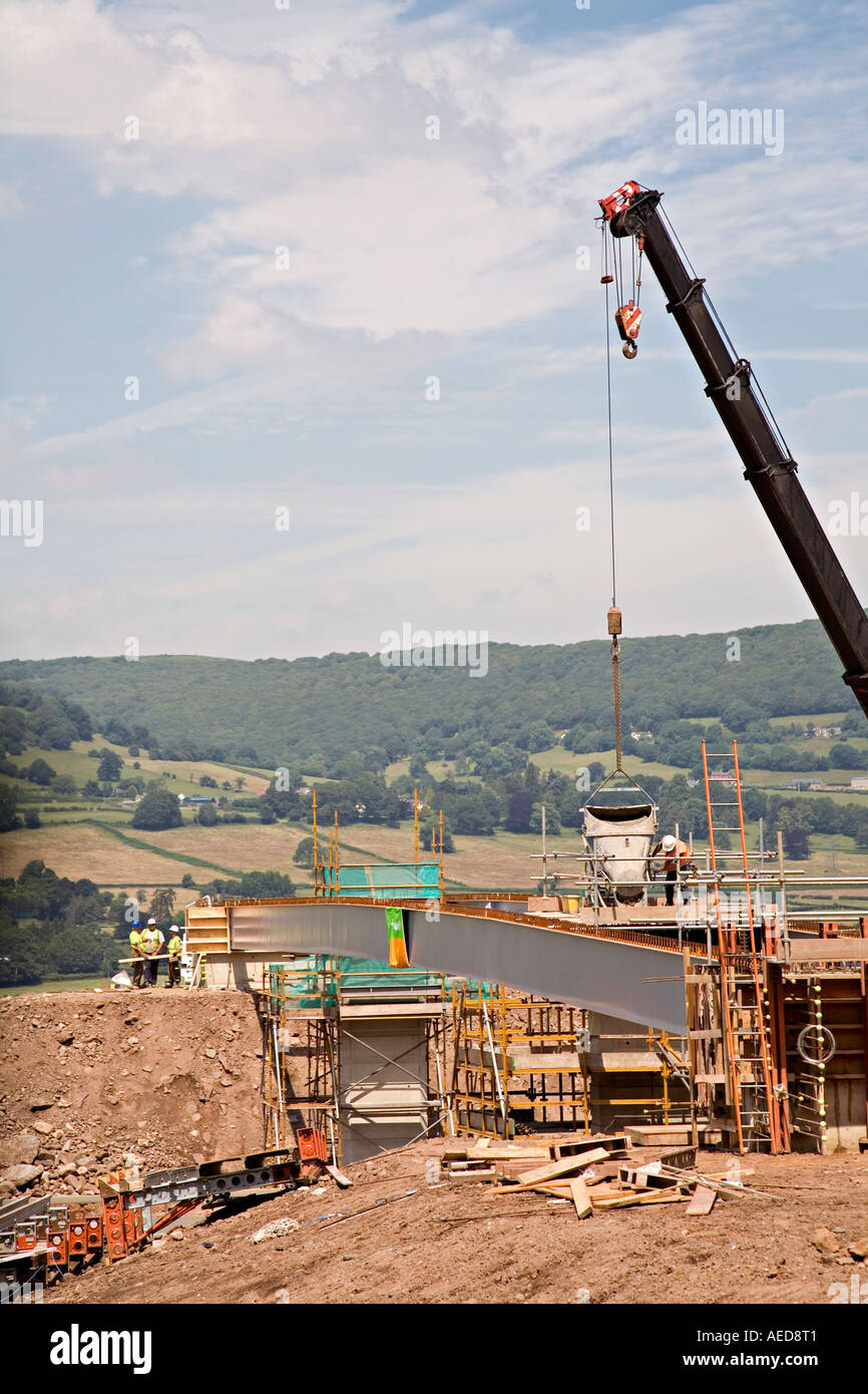 Pouring concrete from a hopper brought by crane to make a new bridge
