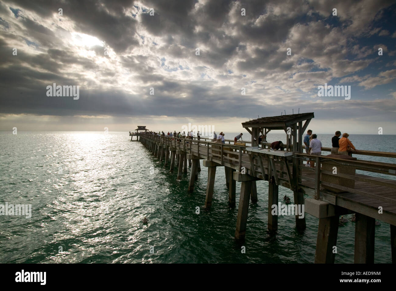 The old wooden pier at Naples beach with dramatic stormy sky and shafts of sunlight over the sea Stock Photo