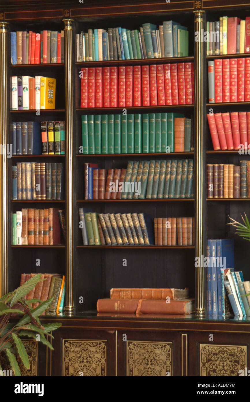 A tall old dark wooden bookcase with shelves of books in a room Stock Photo