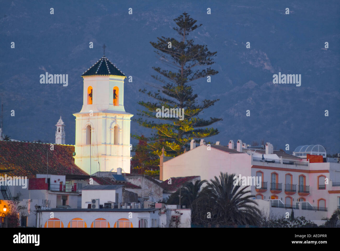 Evening shot of church steeple in Nerja Spain with bell tower lights contrasting with the dark of night Stock Photo