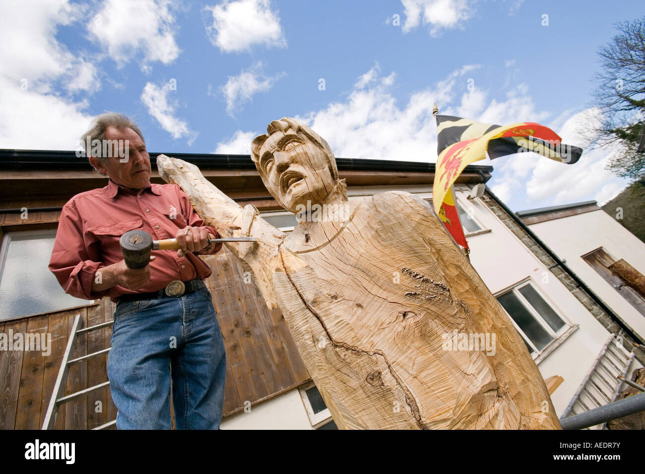UK Wales Powys Builth Wells sculptor David Willams shaping Owain Glyndwr statue with flag behind Stock Photo