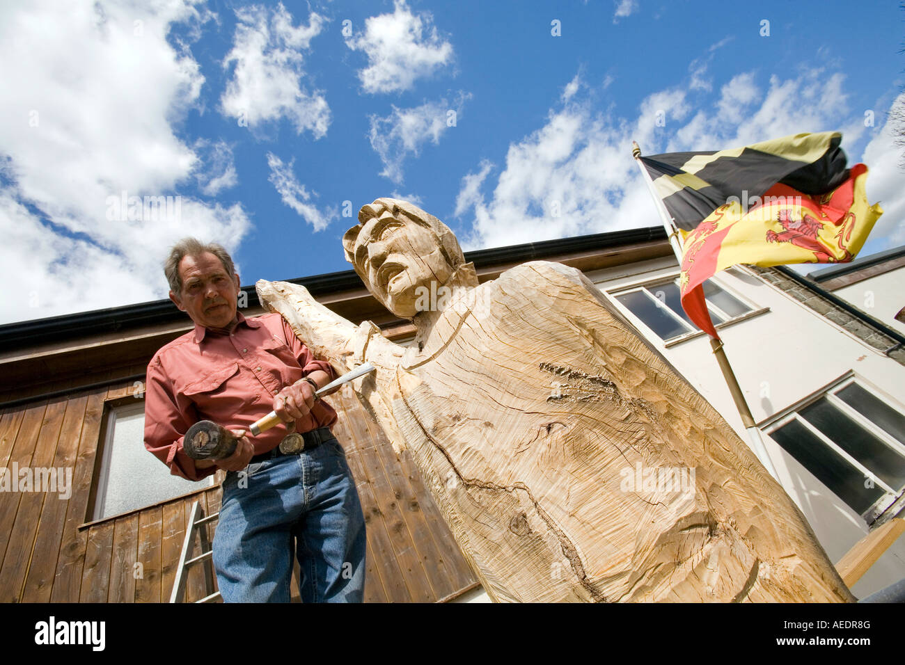 UK Wales Powys Builth Wells sculptor David Willams shaping Owain Glyndwr statue with flag behind Stock Photo