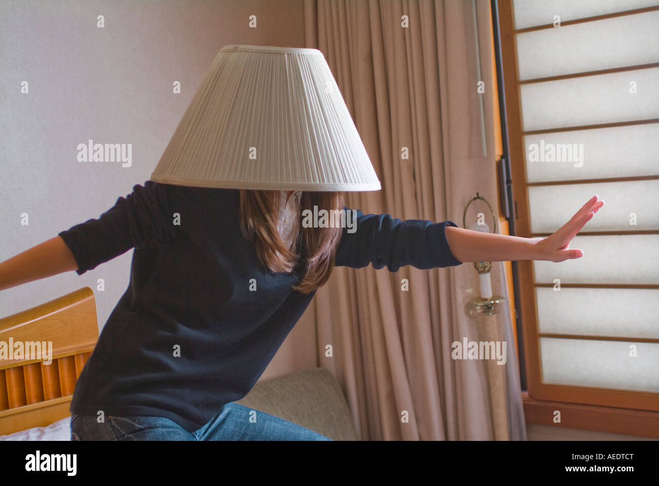 Young woman pretending to surf with a lampshade on her head acting