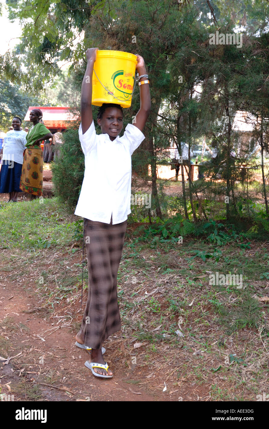 A young black African woman carrying a bucket of water on her head at