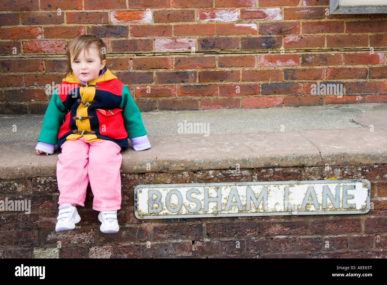 Little girl sitting on a wall in Bosham Lane Bosham Stock Photo Alamy