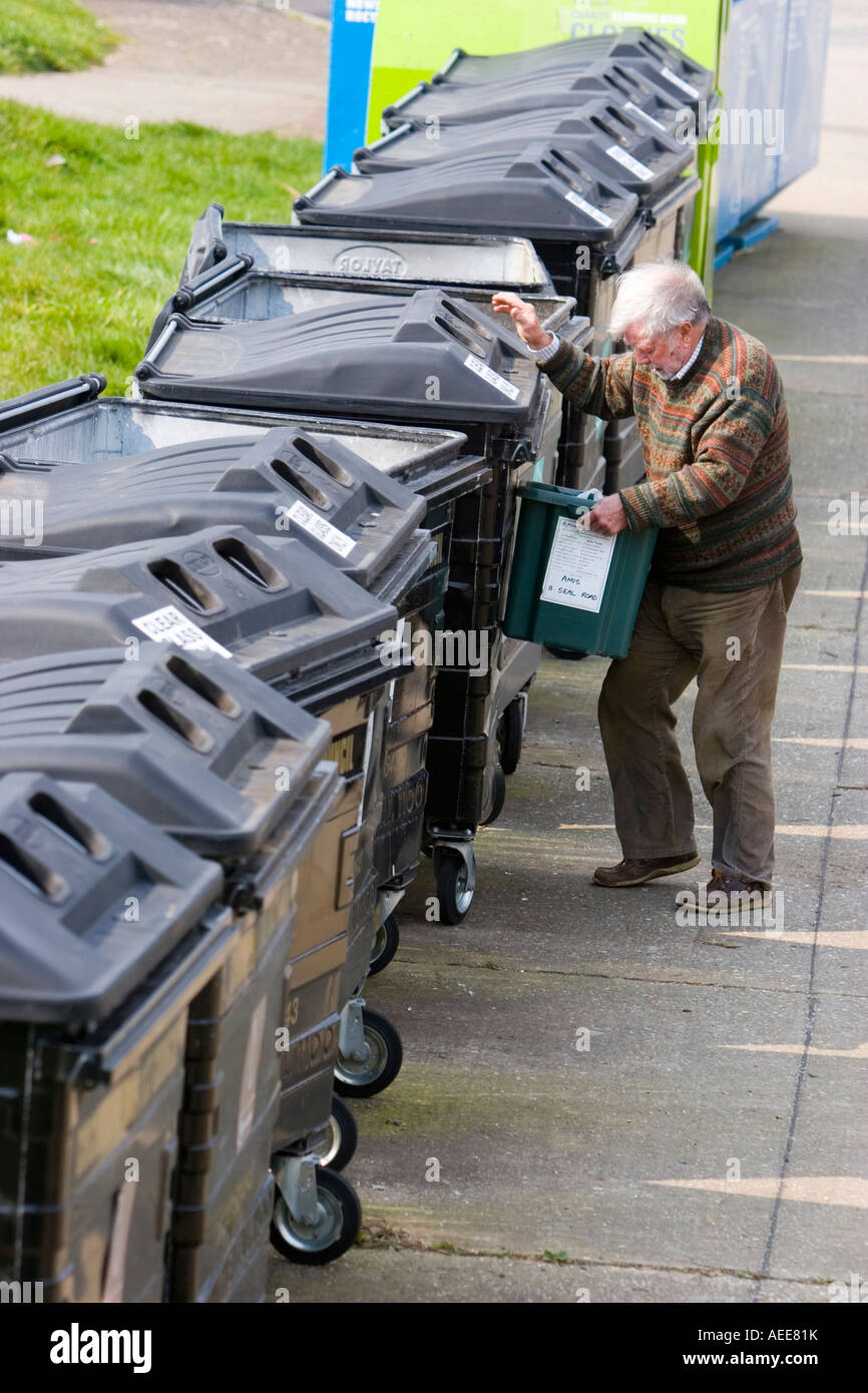 Man putting his glass bottles in the glass recycling bins Stock Photo