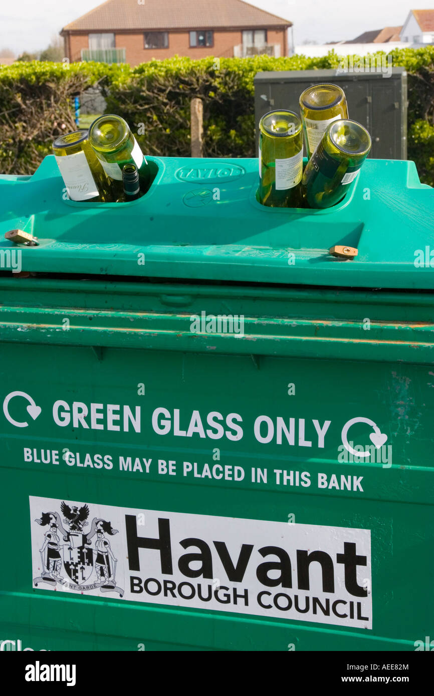Glass recycling bin overflowing with green glass wine bottles Stock