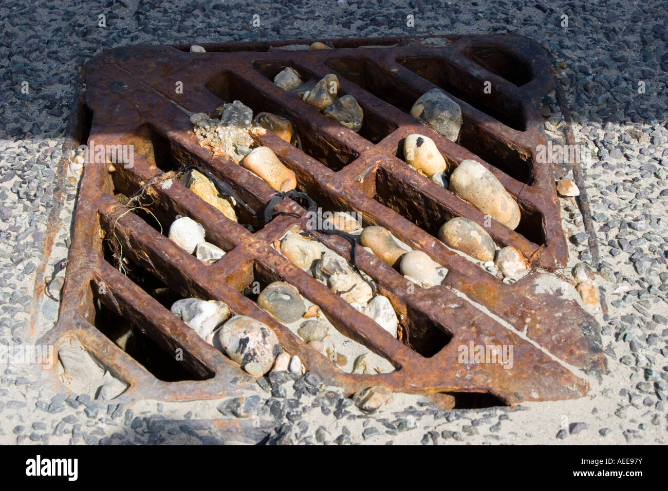Pebbles wedged in the grate of a storm drain Stock Photo