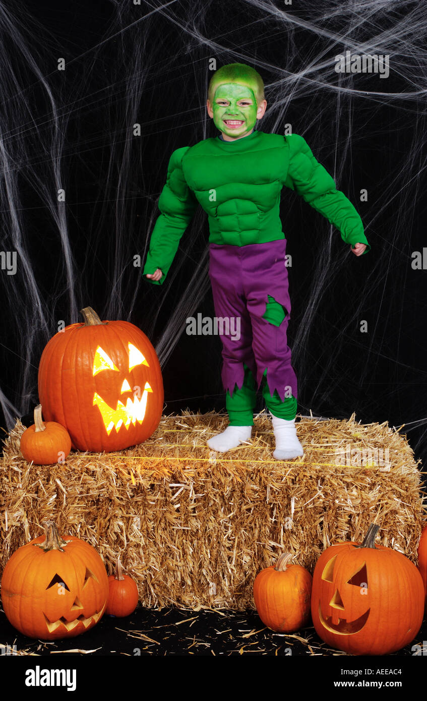 Boy in Incredible Hulk costume standing on bale of hay with jack o lanterns Stock Photo
