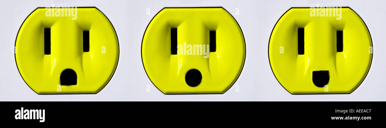 Three yellow electrical outlets that look like faces Stock Photo