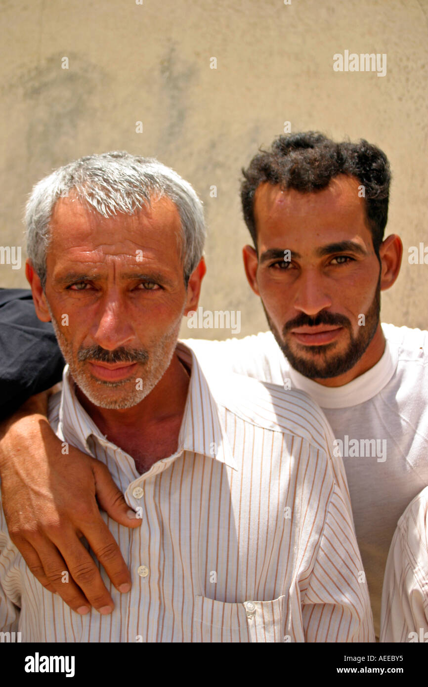 Two Iraqi males pose for the camera next to a building in the Rumaylah oilfields Iraq 2005 Stock Photo
