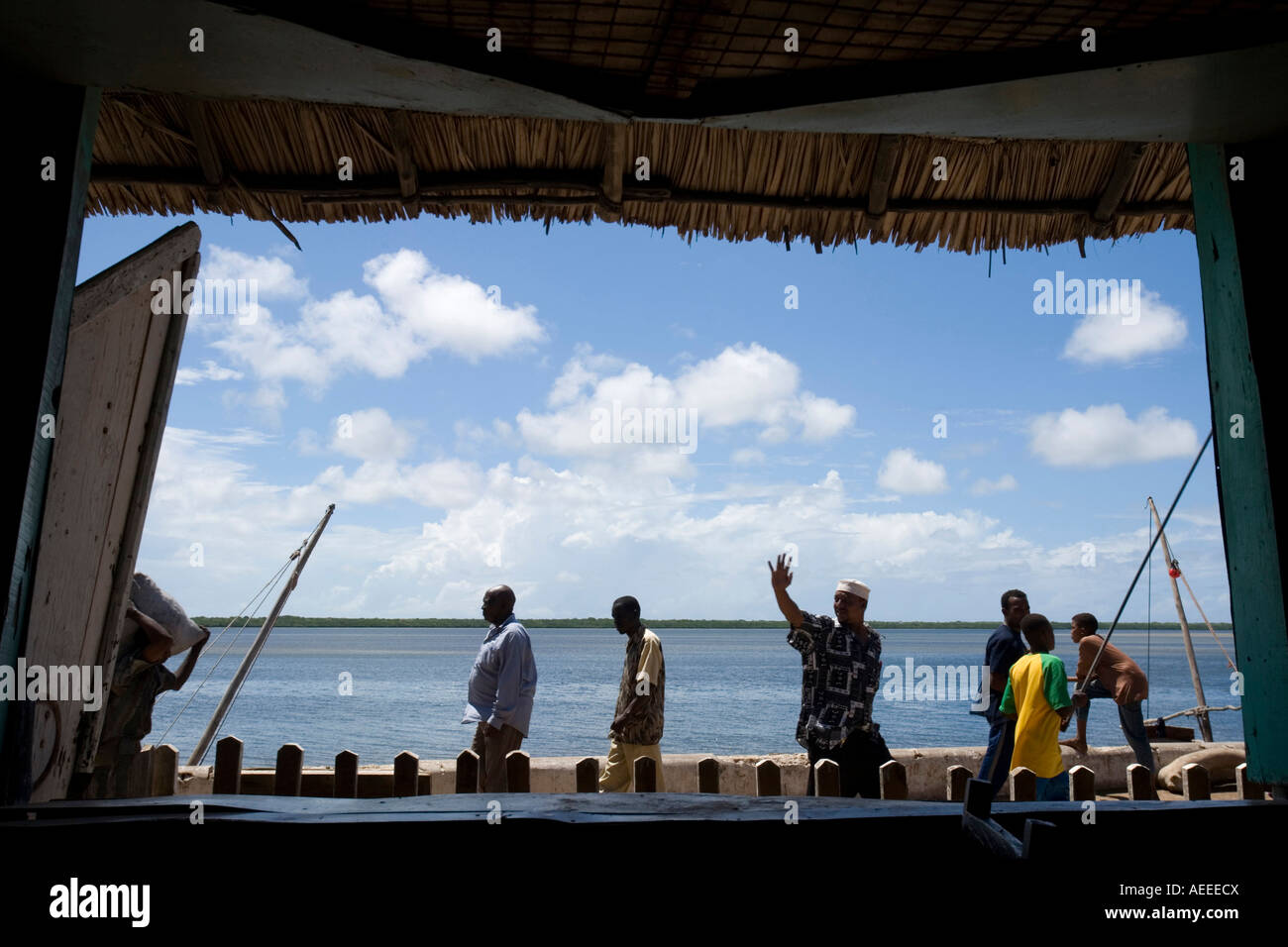 Men walking by on seafront seen through window in Lamu Kenya Stock Photo