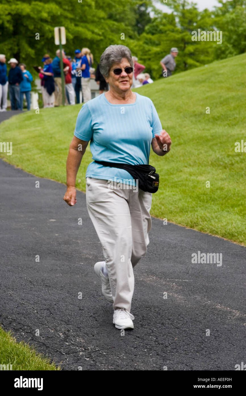 Active elderly woman starting her lap in a relay walking race at a retirement community Stock Photo