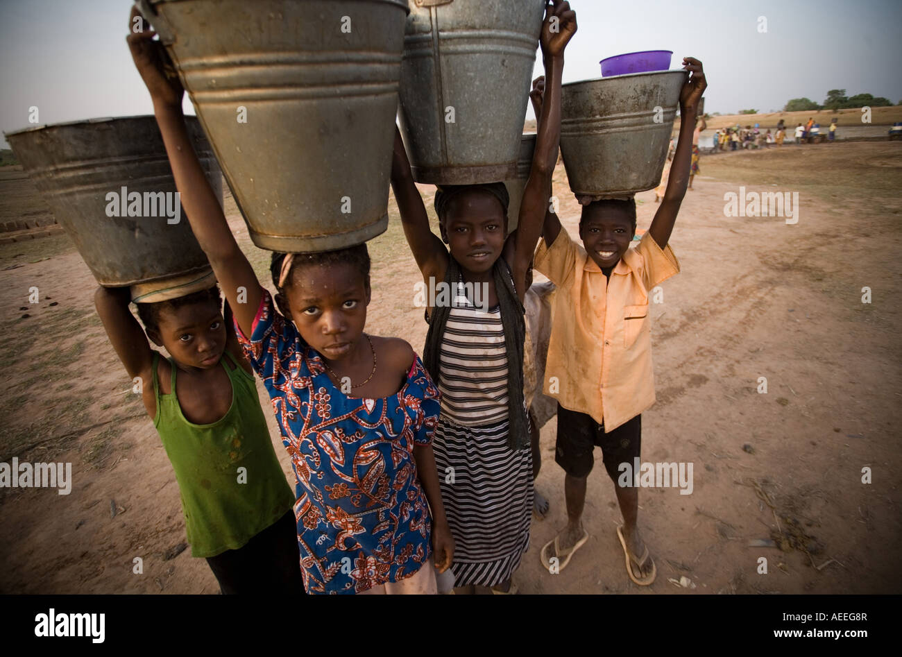 Children carrying water buckets on their heads Stock Photo - Alamy