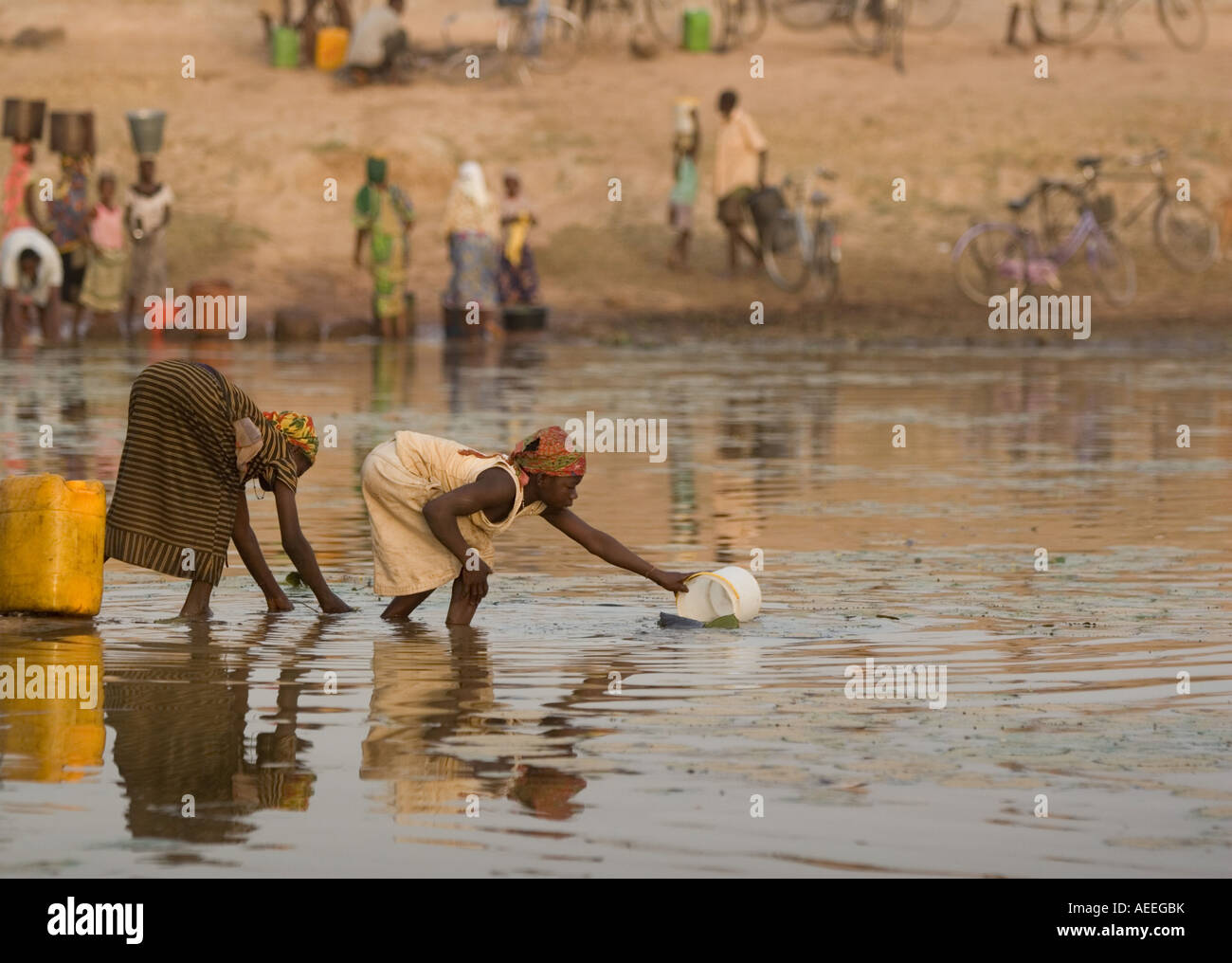 Women fill containers with water at a dam Stock Photo Alamy