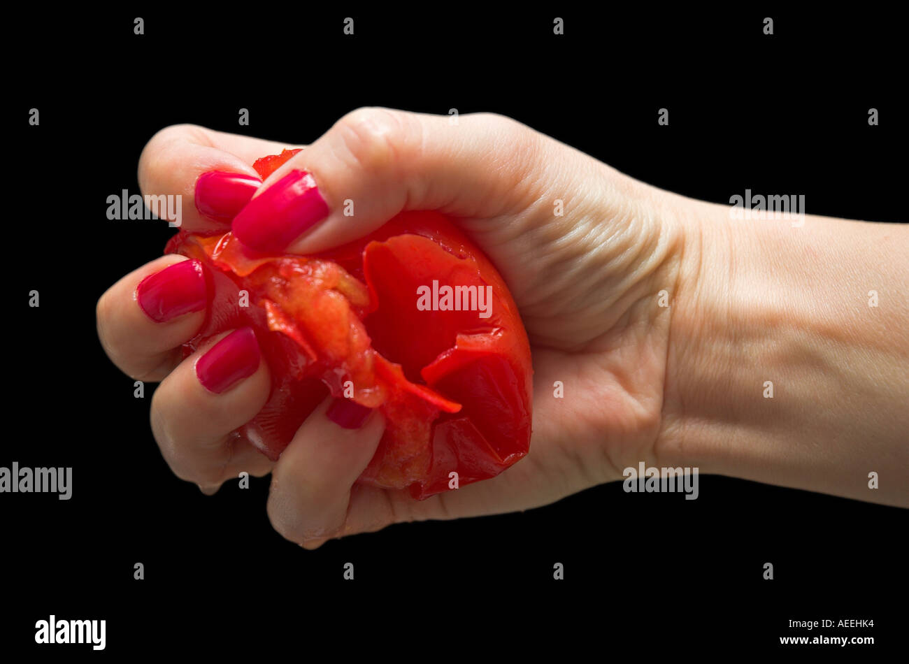 Woman squeezing tomato in hand close up Stock Photo