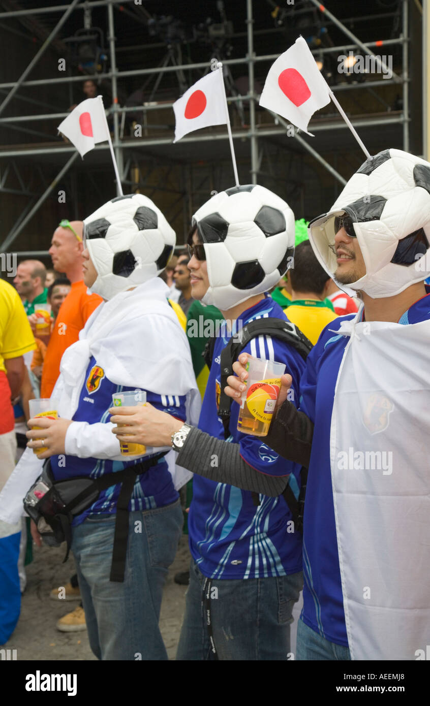 Three Japanese football fans wearing hats looking like footballs at a football world cup public viewing event in Dortmund Stock Photo