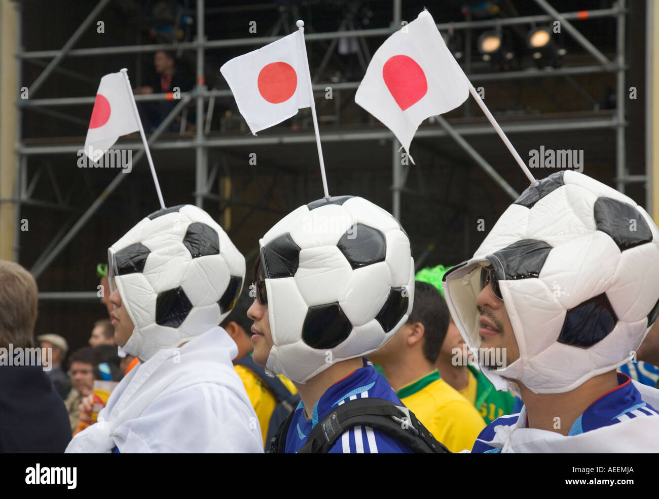 Three Japanese football fans wearing hats looking like footballs at a