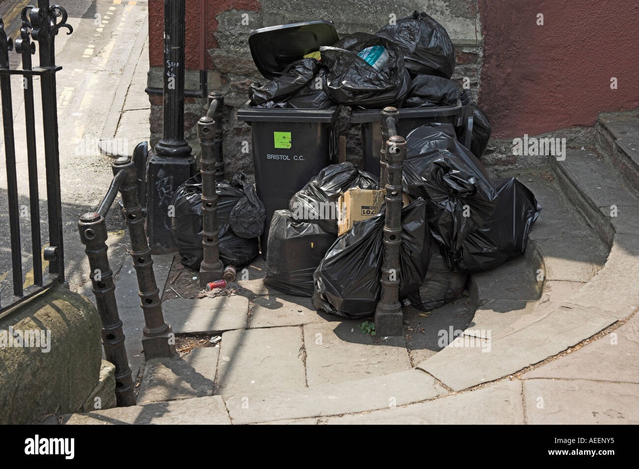 Overflowing black rubbish bags and wheely bin waiting for collection