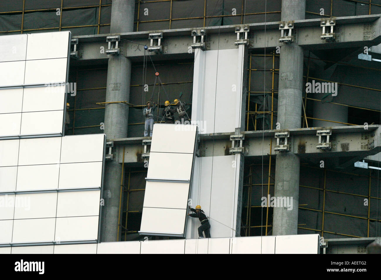 Shanghai China Construction workers positioning cladding panels on a new sky scraper being built in the centre of Shanghai Stock Photo