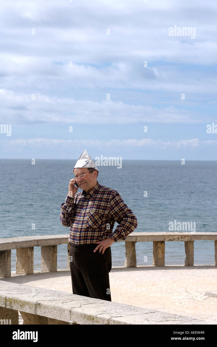 A portuguise man with paper hat answers his mobile phone whilst on a jetty in Albufera Portugal Stock Photo