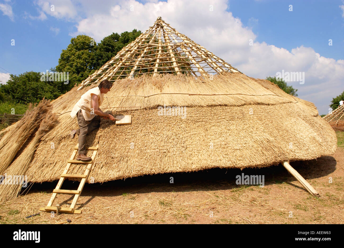 Thatching roof of Iron Age roundhouse being built using traditional
