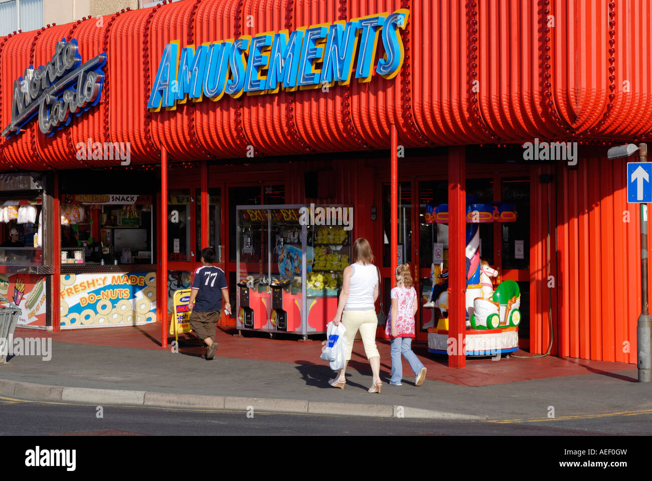 Tourists walking along Rhyl promenade by an amusement arcade in the