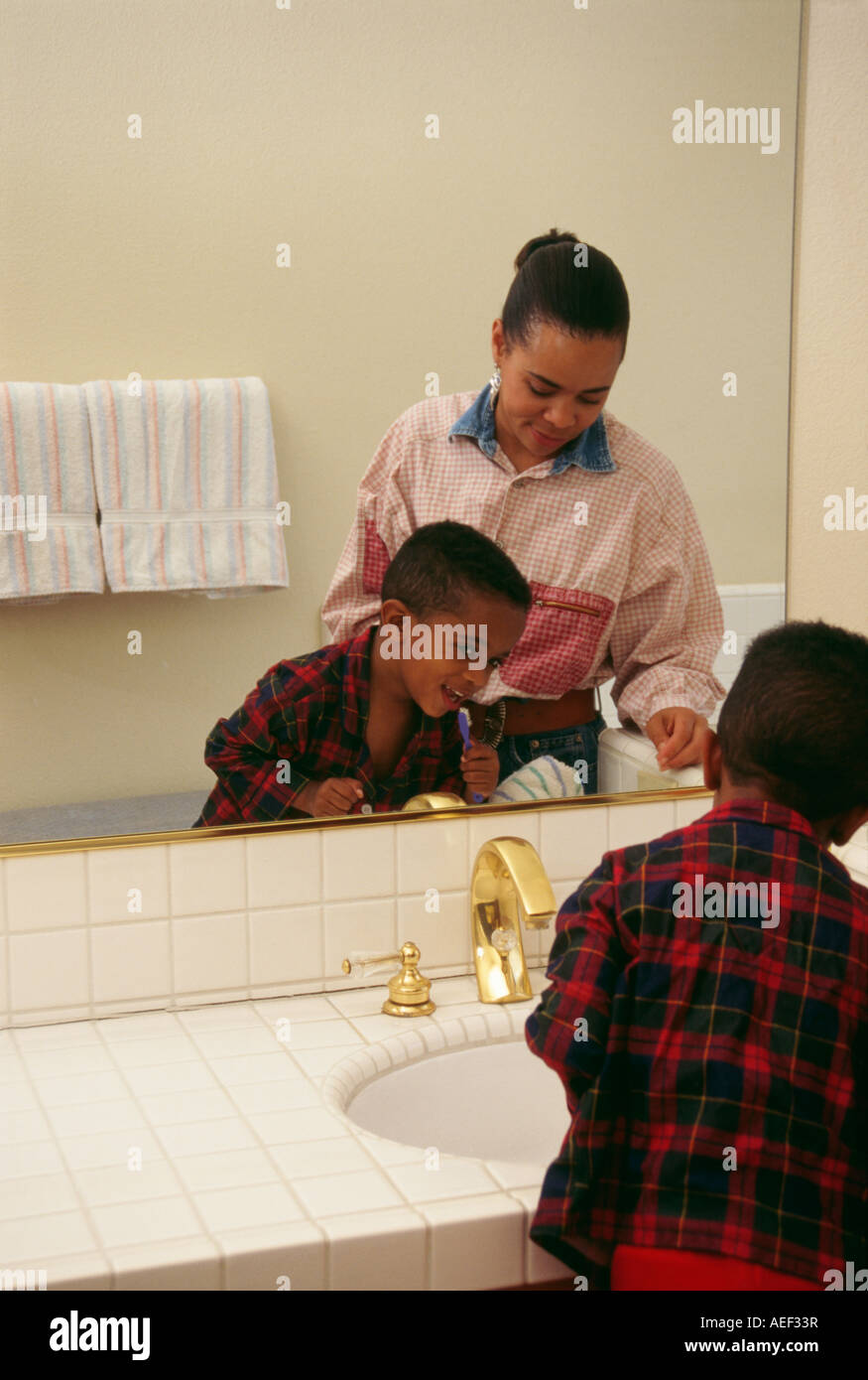 Boy 5-6 year old  brushing teeth holding toothbrush smiling rear view Stock Photo