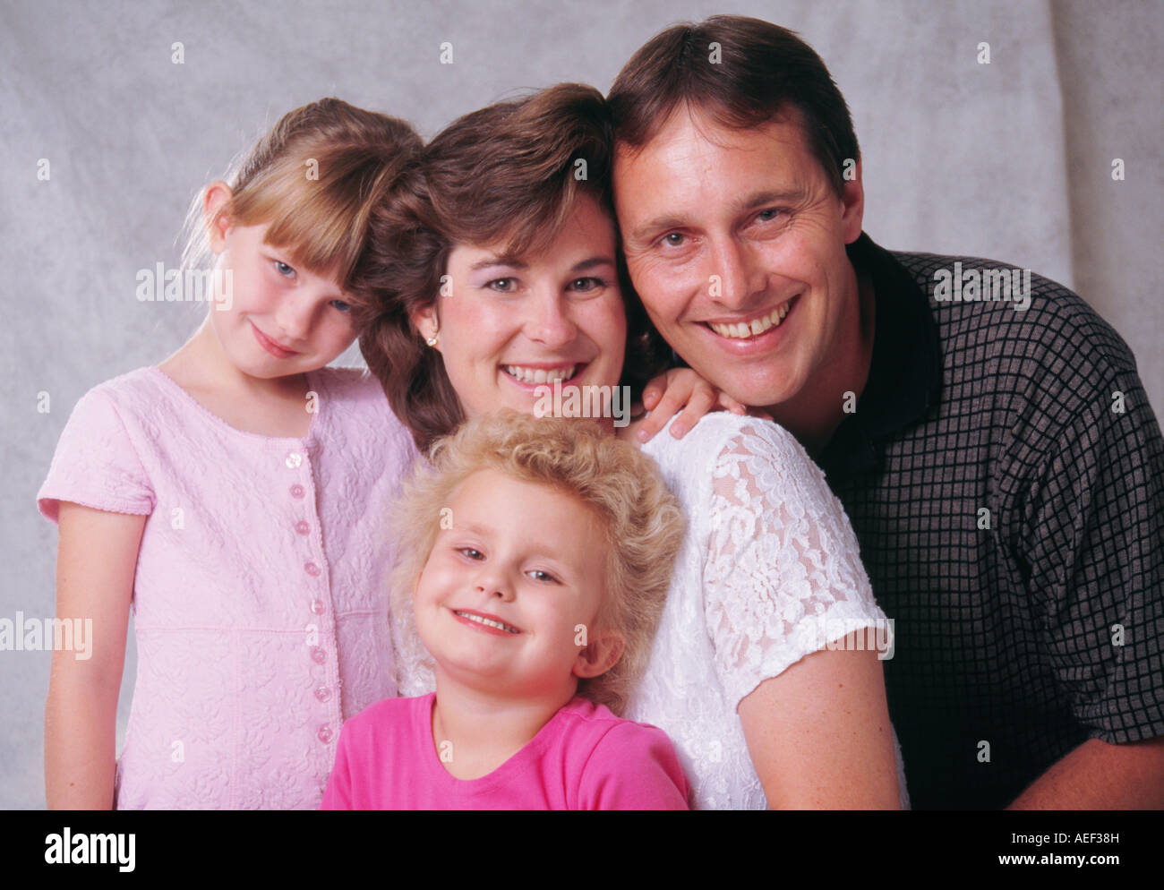 Family portrait ,Mom Dad two girls 2-3 4-5 year olds old Caucasian smiling heads together Stock Photo
