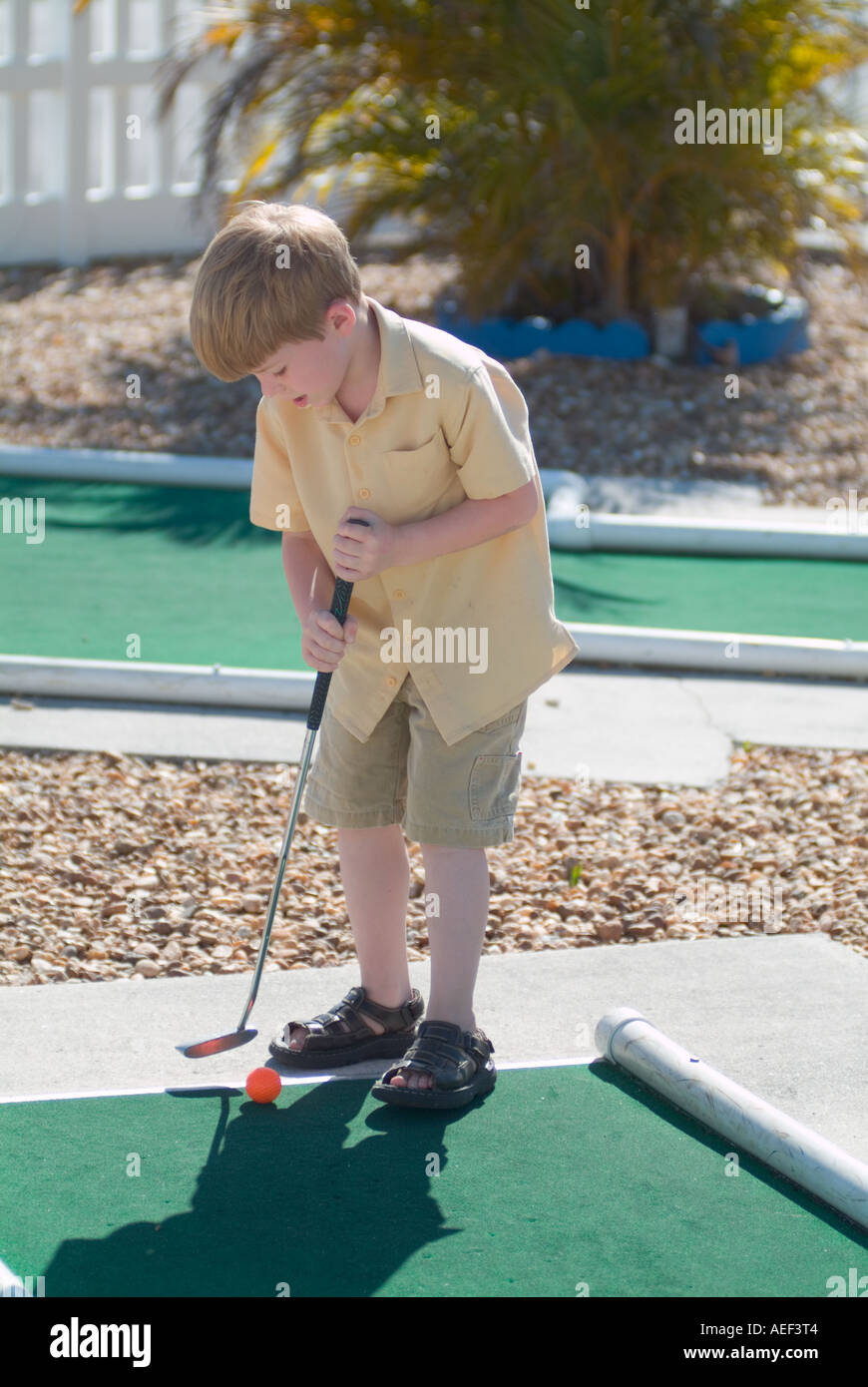boy playing miniature golf child children course coordination skills golfing Stock Photo