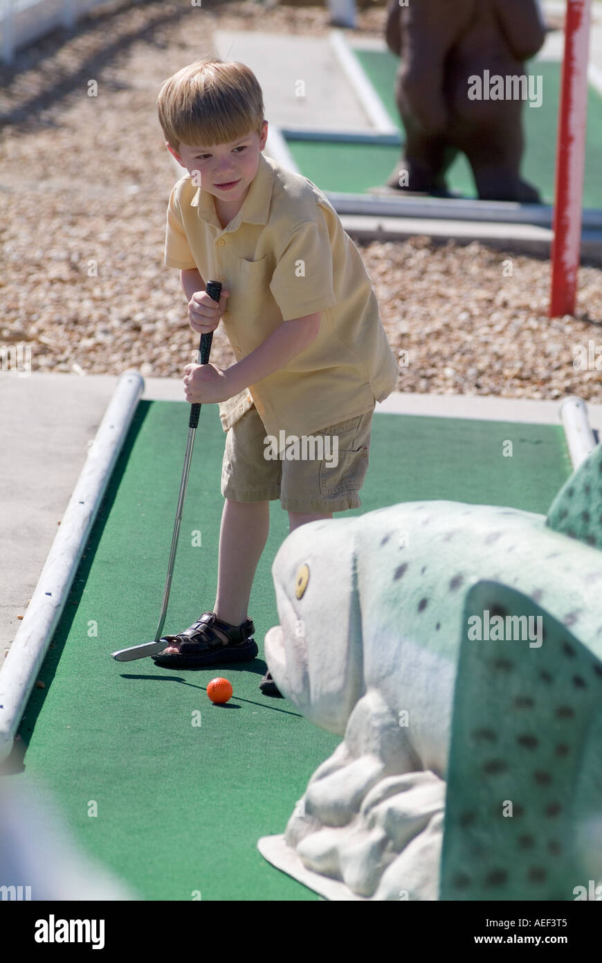 boy playing miniature golf child children course coordination skills golfing Stock Photo