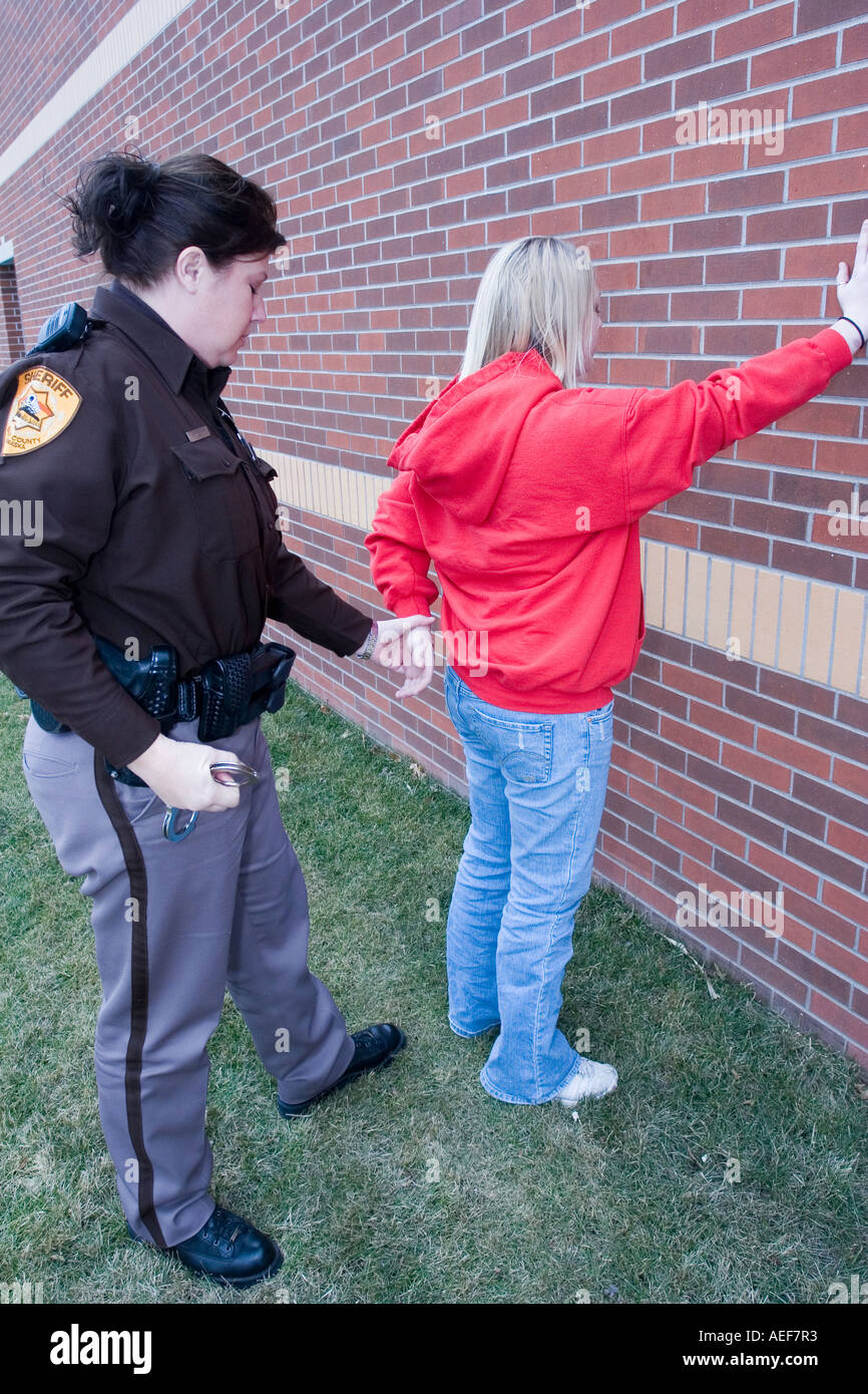 Young female being arrested by female deputy sheriff Saline County Sheriffs Office Nebraska Stock Photo