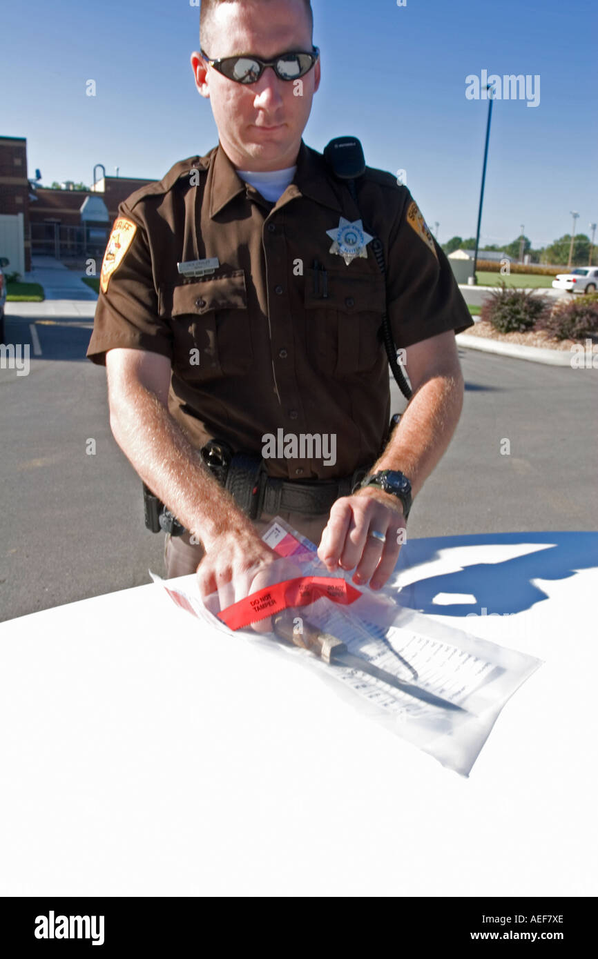 Deputy Sheriff placing confiscated evidence in bag for lab analysis. Stock Photo
